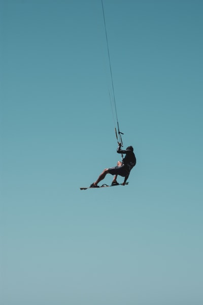 Men black jacket and black trousers under the blue sky on the black rope during the day
